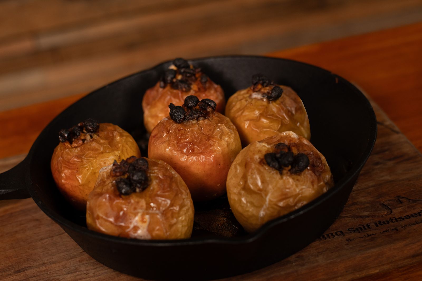 Golden baked apples with raisins and spices in a cast iron pan, cooked in a wood fired pizza oven.