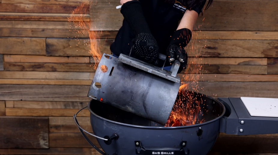 Hand pouring hot charcoal from a chimney starter into a SNS Kettle with sparks flying as the coals ignite. Hand pouring hot charcoal from a chimney starter into a SNS Kettle with sparks flying as the coals ignite.
