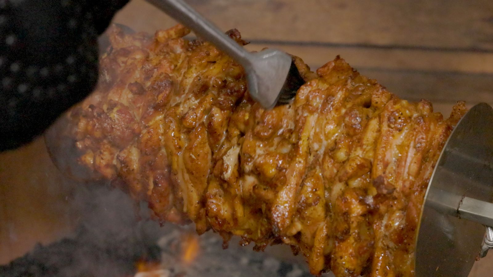 Close-up of juicy chicken gyros cooking on a rotisserie over charcoal, being basted for flavour and shine during grilling Close-up of juicy chicken gyros cooking on a rotisserie over charcoal, being basted for flavour and shine during grilling