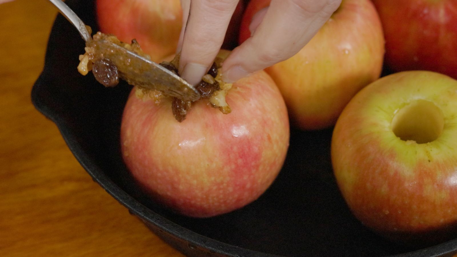 Close-up of an apple being filled with a mixture of honey, walnuts, raisins and cinnamon before baking.