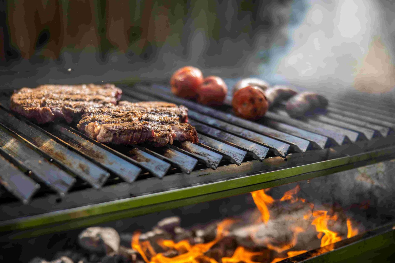 Steaks cooking on parrilla grill over live charcoal fire