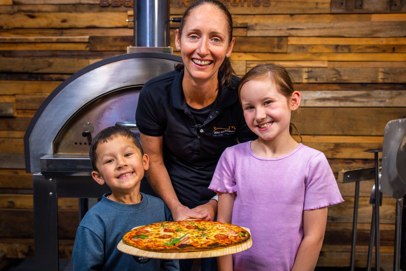 Family enjoying freshly cooked pizza made in a Flaming Coals premium wood fired pizza oven