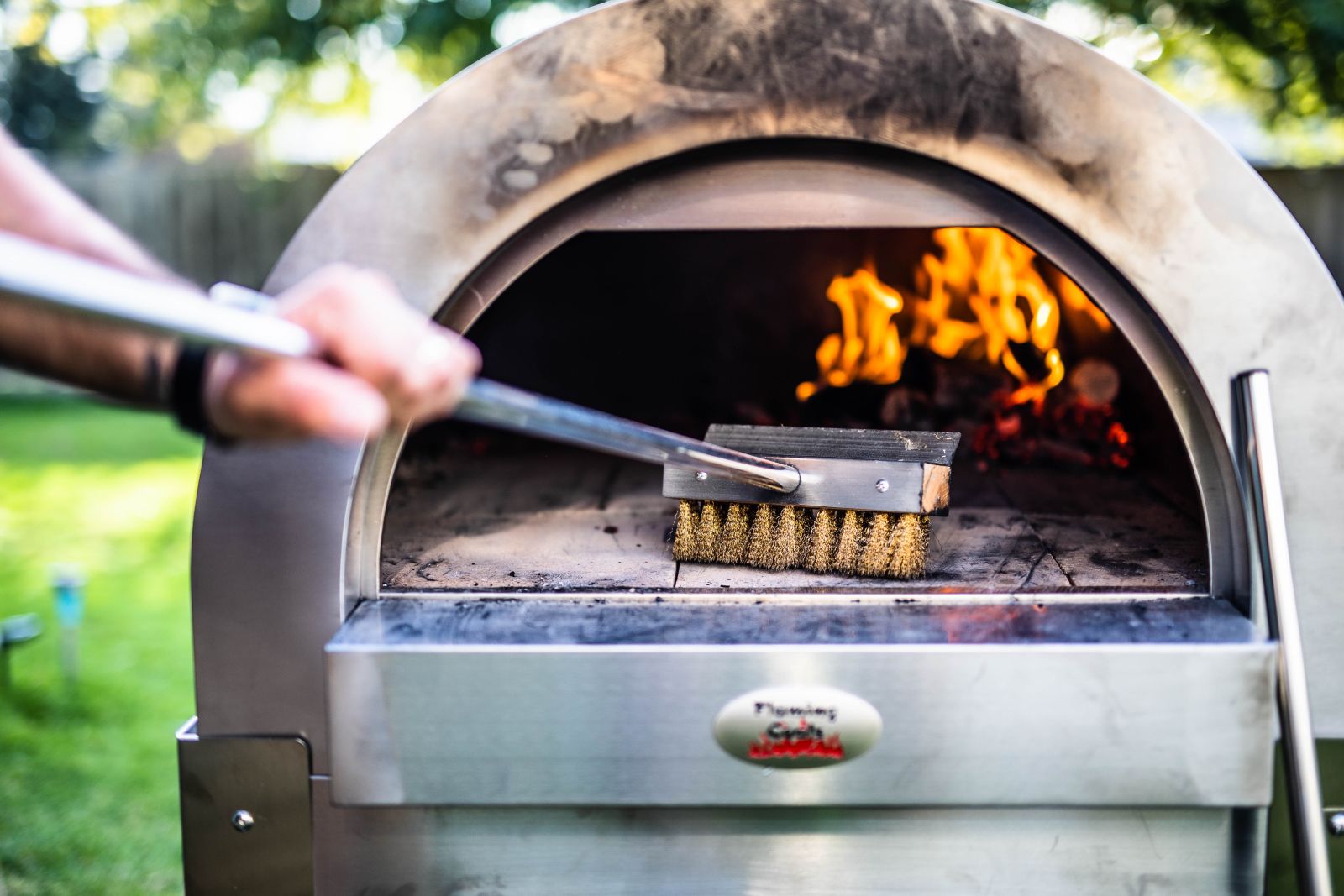 This image shows a pizza brush used on a pizza oven.
