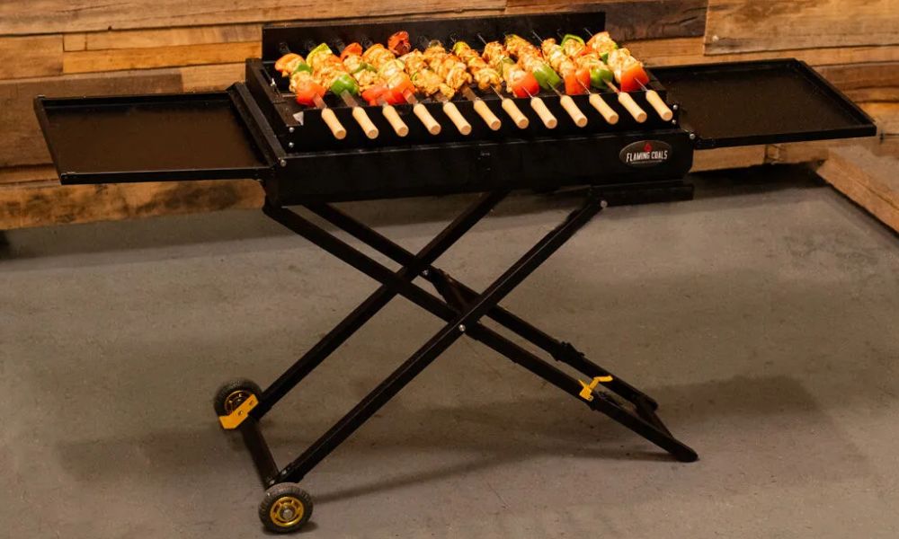 Portable foldable charcoal shashlik grill cooking skewers of chicken and vegetables on raised skewer rack. Portable foldable charcoal shashlik grill cooking skewers of chicken and vegetables on raised skewer rack.