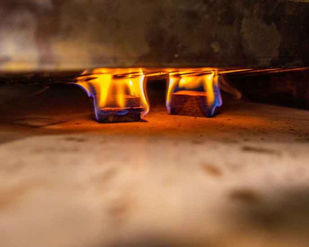 Close-up of natural firelighters igniting with bright orange and blue flames on a BBQ surface. Close-up of natural firelighters igniting with bright orange and blue flames on a BBQ surface.
