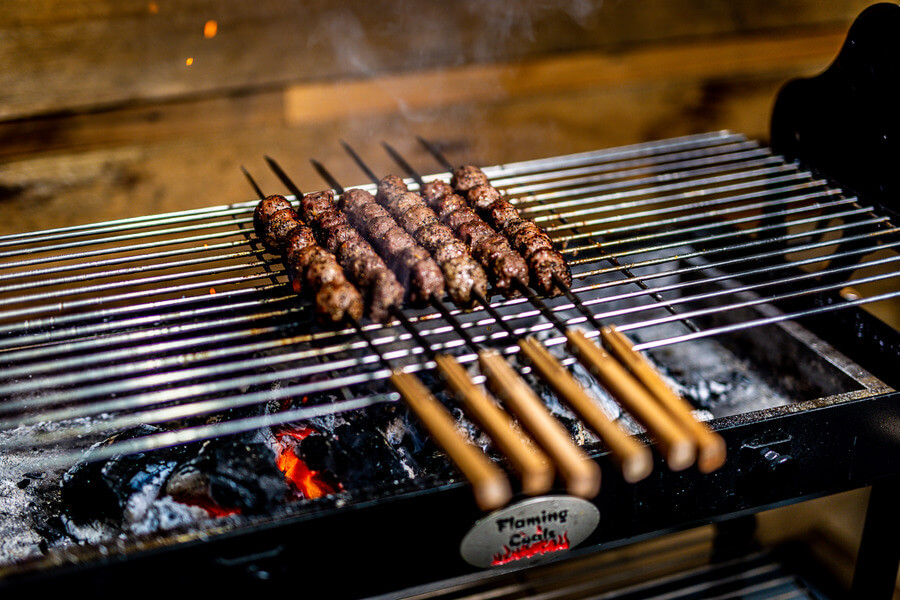 This image shows the flat kebab skewers cooking kebabs.