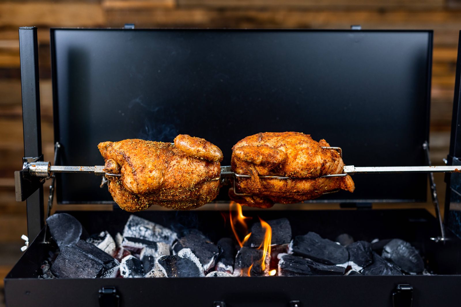 Whole chickens roasting on mini charcoal spit roaster