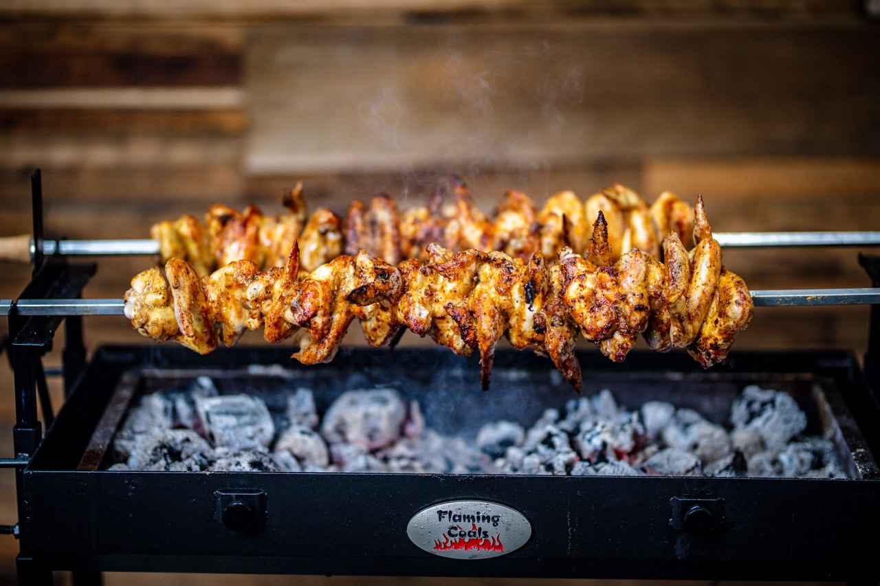 This image shows the Cyprus spit cooking chicken wings.