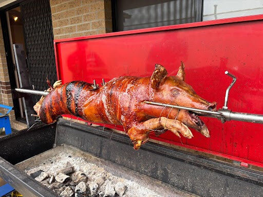 Whole pig roasting on a Flaming Coals Warrior Spit Roaster over charcoal