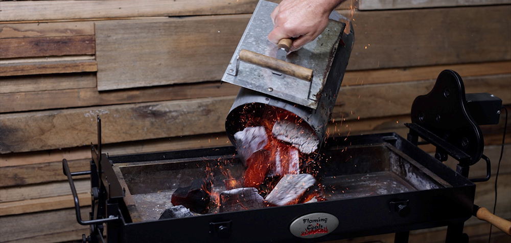 This_image_shows_lit_charcoal_being_added_to_the_spit_rotisserie