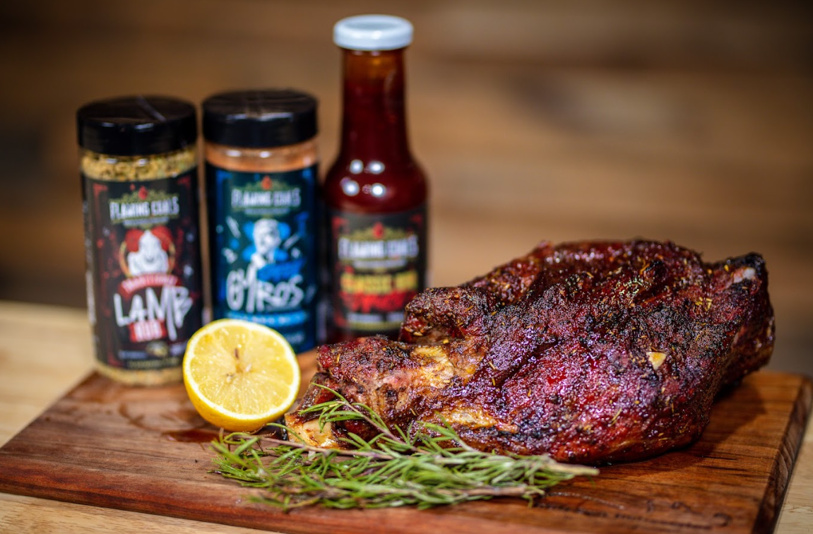 Roast lamb on a wooden board with rosemary and lemon, seasoned with Flaming Coals lamb and gyros BBQ rubs