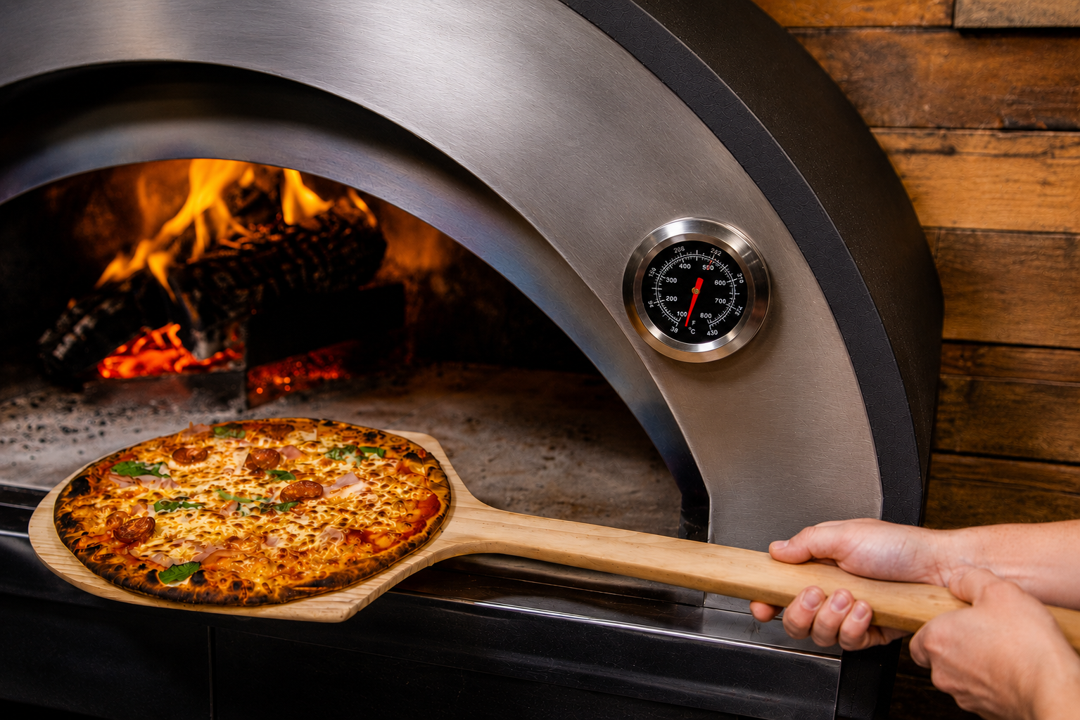 This image shows the long handled wooden pizza peel cooking a pizza.